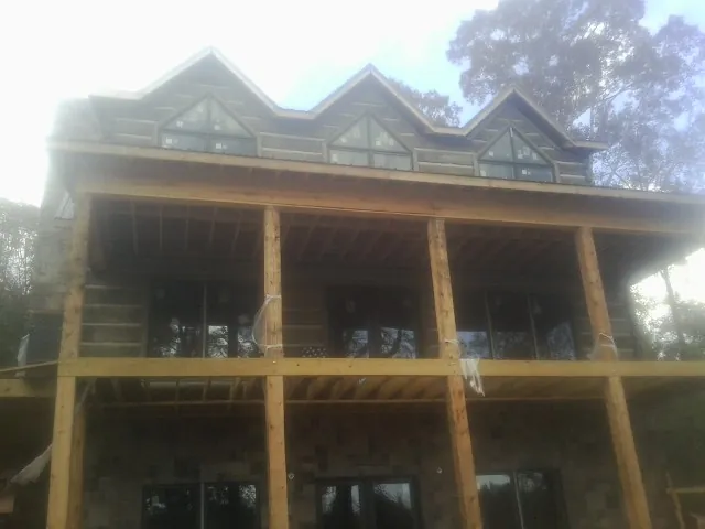 Dormers and porch framing on a large log home under construction — Roof Coating work by our crew in Ellicottville