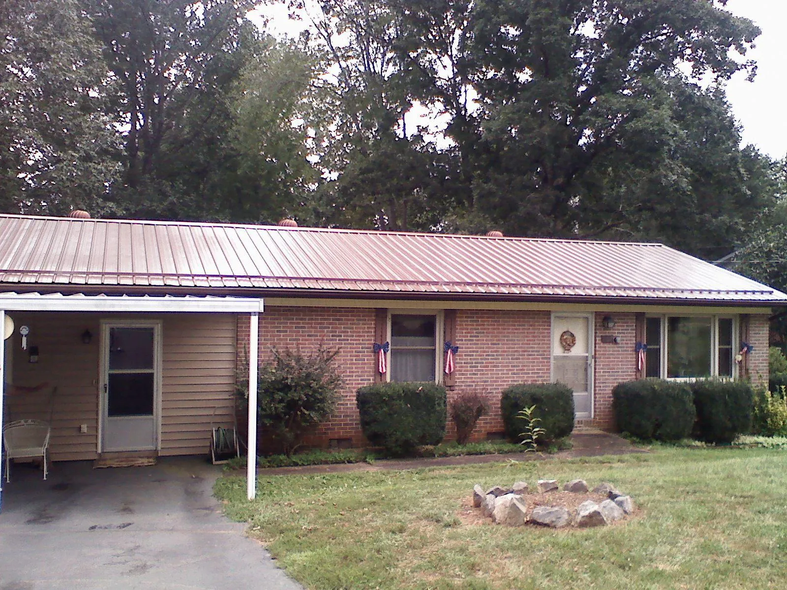 Bronze metal roof and carport on a brick ranch home — Roof Repair work by our crew in Ellicottville