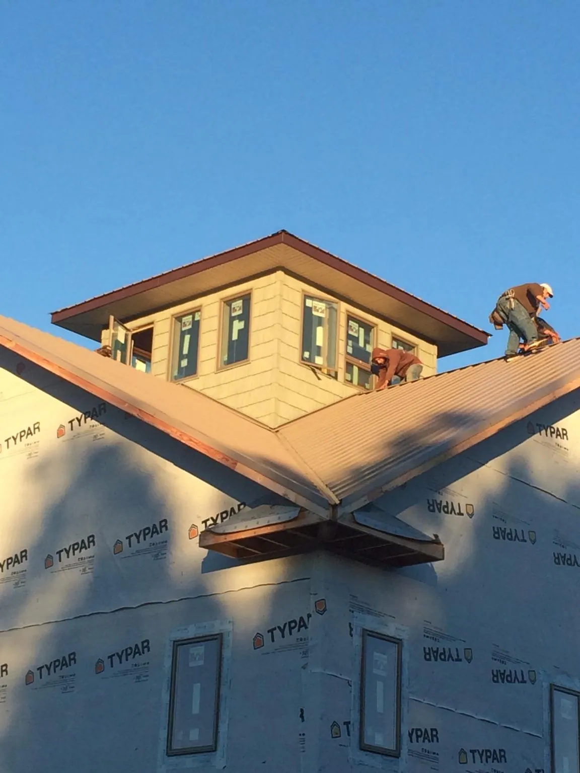 Roofers working around a rooftop cupola on a new metal roof at sunset — Roof Waterproofing in Ellicottville by Roofing Brothers